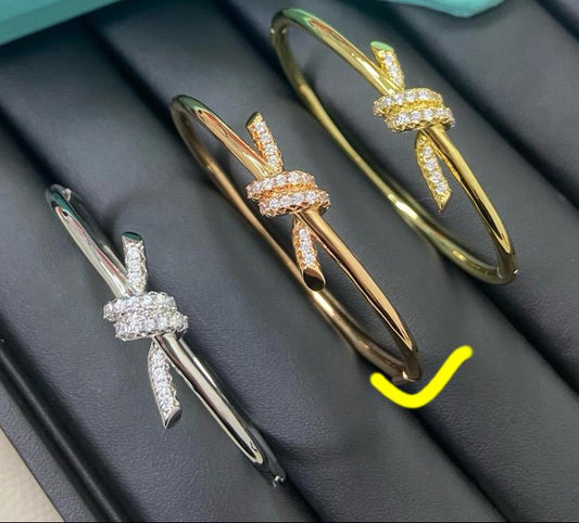 This pave love knot bangle bracelet with sparkling stones is designed to turn everyday style into something unforgettable. symbolizing strength, connection, and individuality. 